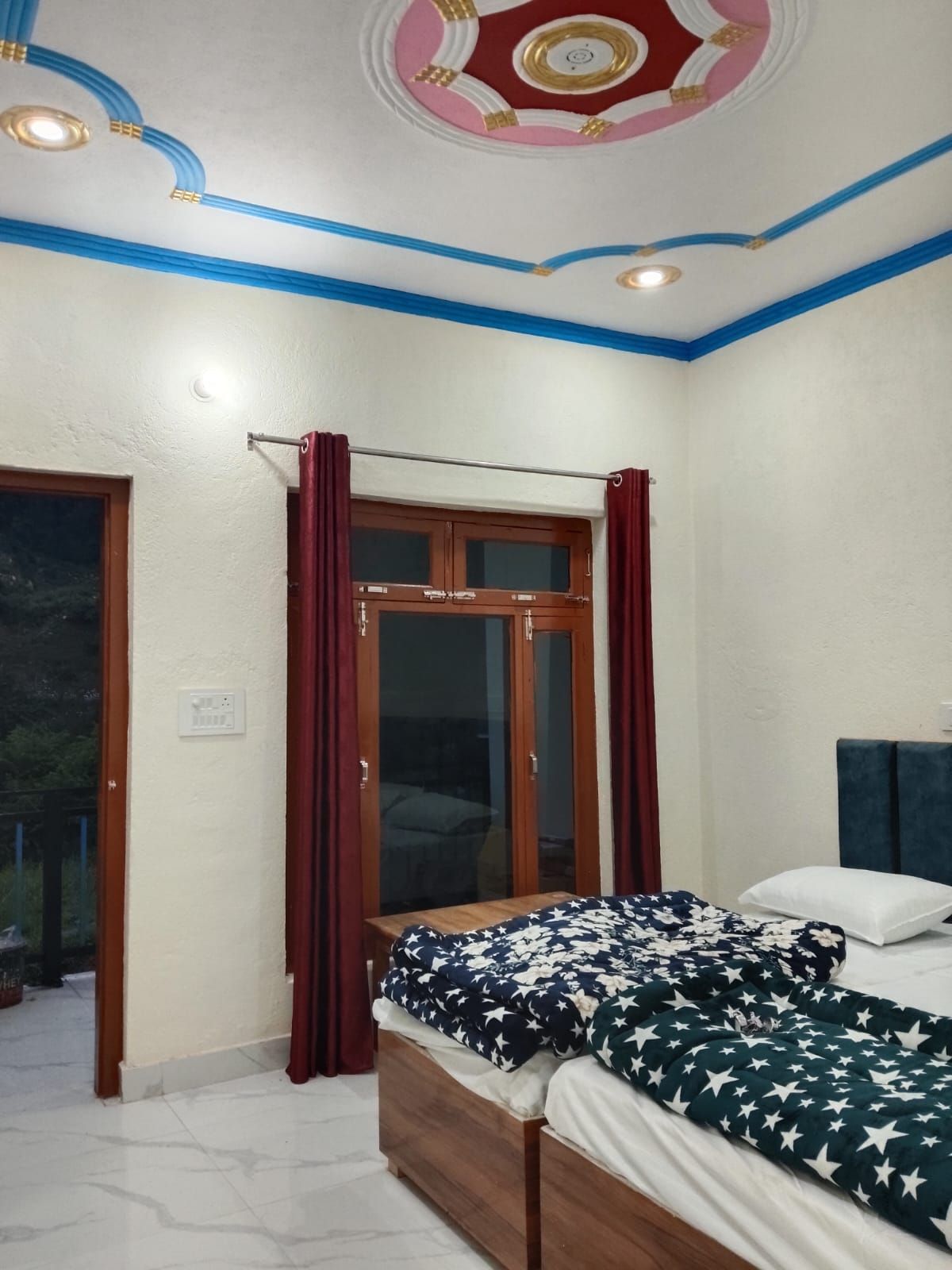 Un dormitori amb llit, finestra amb cortines, sostre amb elements decoratius i porta.