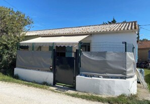 A small building with a tiled roof, a covered entrance, and a fenced area. - The Blue Tamarisk Fisherman's Cottage (Port-Saint-Louis-du-Rhône)