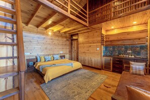Ein gemütliches Holzhaus-Interieur mit einem Bett, einem Schreibtisch und einer Küchenzeile.