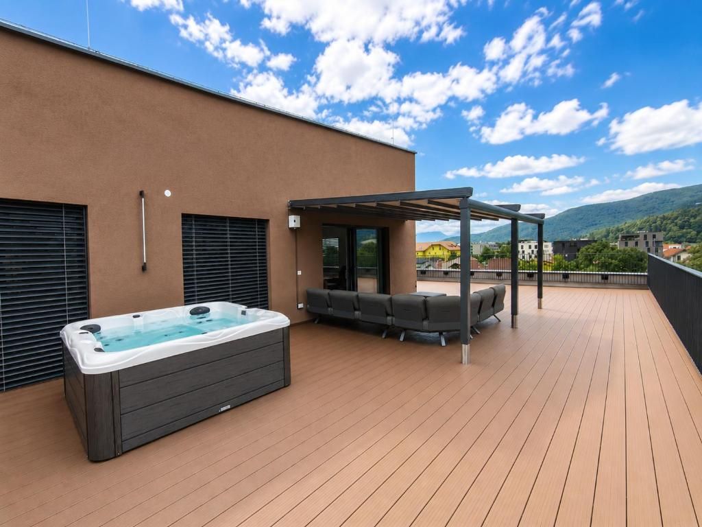 A rooftop deck with a hot tub, outdoor seating, and a pergola.