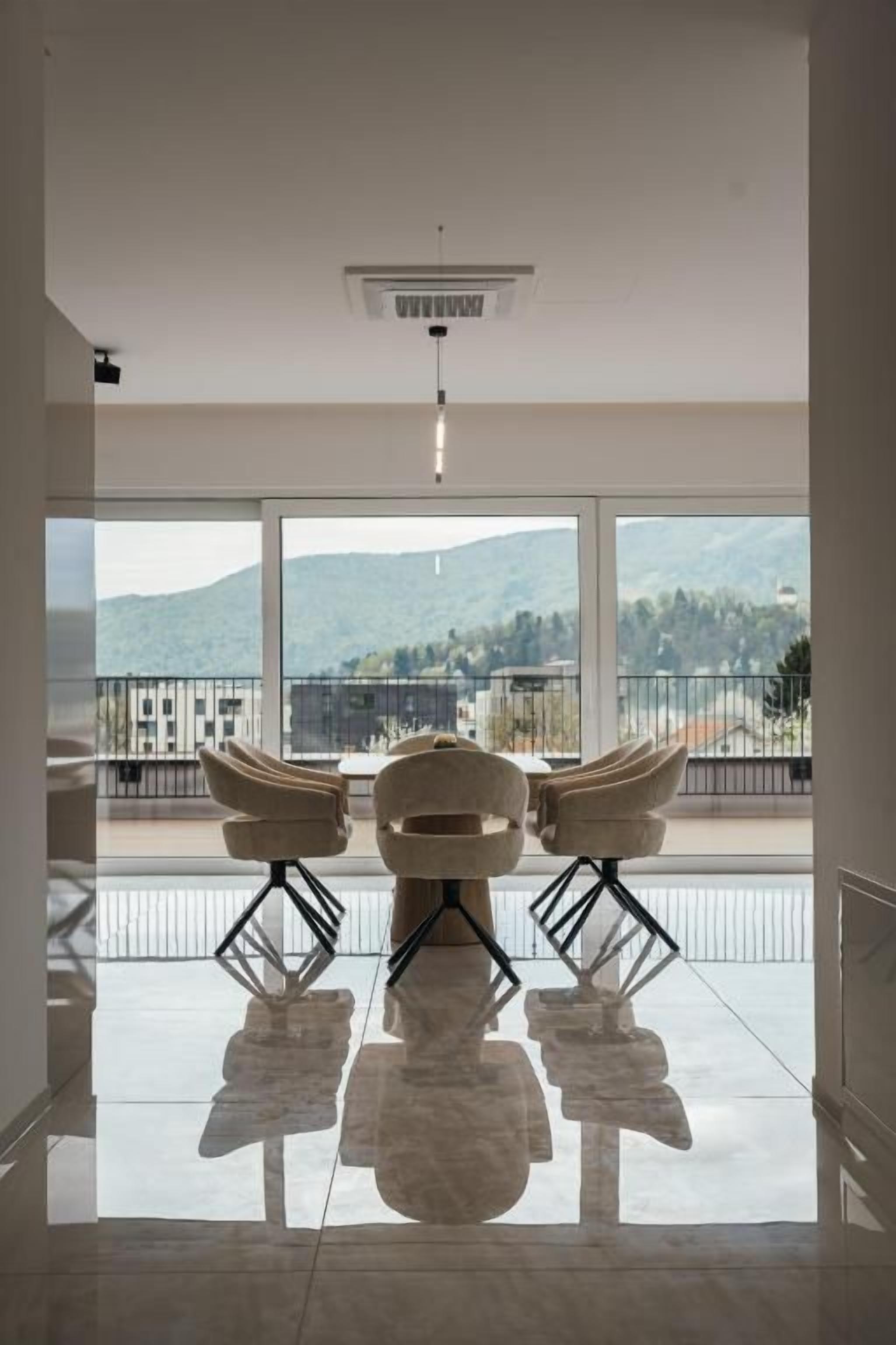 Une pièce spacieuse avec une grande fenêtre, un fauteuil moderne et un luminaire fixé au plafond.