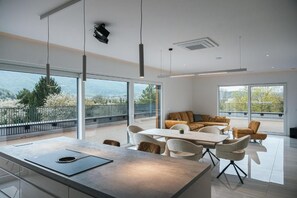 Una cocina moderna con una isla central, comedor con sillas y un sofá.