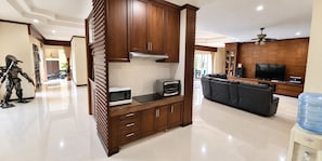 A modern kitchen with built-in appliances, a dining area with a sofa, and a water dispenser. - Private 5-bedroom Pool Villa in Middle of the Island Phuket (Kathu)