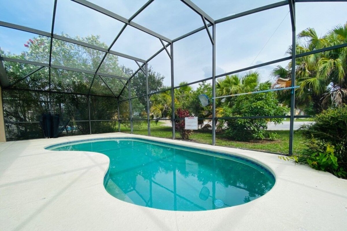 An indoor swimming pool with a clear view of the surrounding greenery and a covered area.
