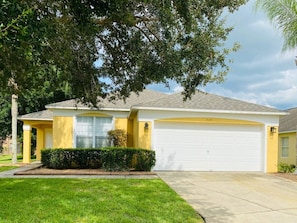 A residential house with a garage, a driveway, and a well-maintained lawn. - South Facing Pool & Game Room! 6 Bedroom Home (Haines City)