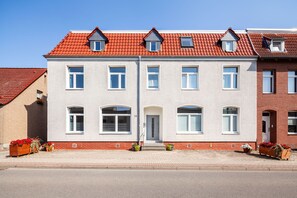 Ein zweigeschossiges Wohngebäude mit rotem Ziegeldach, zahlreichen Fenstern und einer Ziegel-Fassade.
