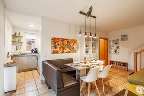 Eine moderne Küche mit Essbereich, einer Couch und einem Tisch für vier Personen.