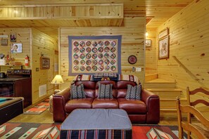 Ein gemütliches Blockhaus-Interieur mit einem Ledersofa, einer gesteppten Wanddeko und einer Holztreppe.