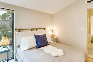 A bedroom with a bed, bedside table, lamp, and a view of the outside. - Sip, Dine & Explore: Central Denver Escape! (Denver)