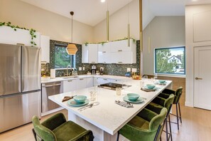 A modern kitchen with a central island, stainless steel appliances, and a view of a house through the window. - Sip, Dine & Explore: Central Denver Escape! (Denver)