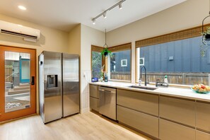 A modern kitchen with stainless steel appliances, a built-in dishwasher, and a window with a view of the backyard. - Walk to RiNo & Coors Field! Modern Denver Home (Denver)
