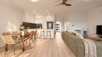 A modern apartment with a dining area, kitchen, living room, and a ceiling fan.