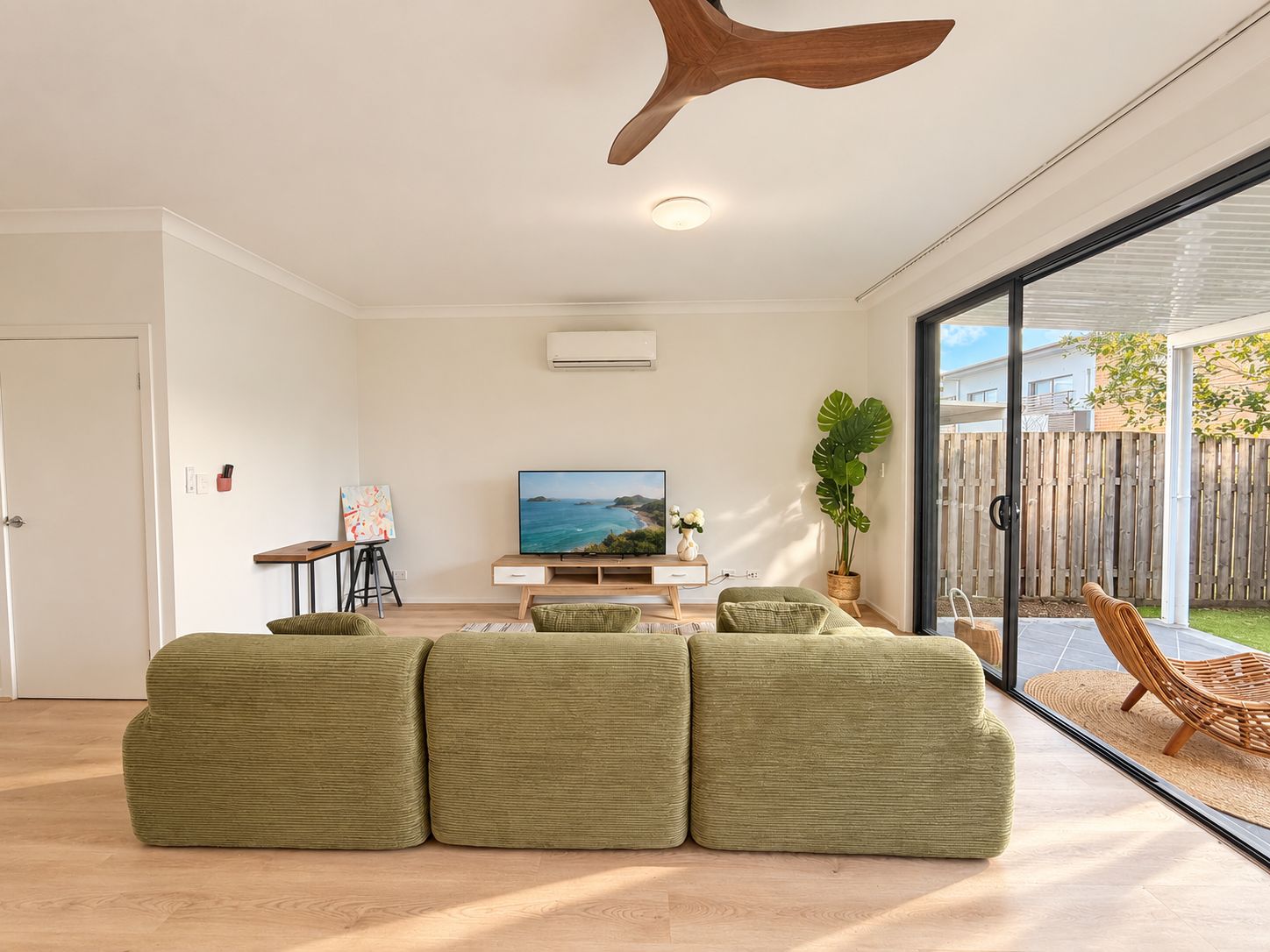 A modern living room with a large window, a flat-screen TV, and a wooden ceiling feature.
