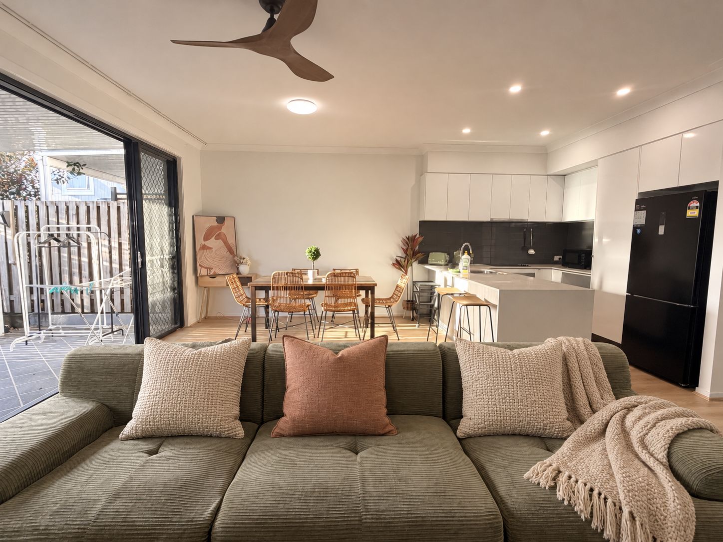 A modern living room with a sofa, cushions, and a dining area with chairs and a table.