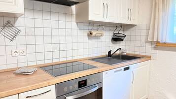 Eine moderne Küche mit weißen Schränken, einer Edelstahl-Dunstabzugshaube, einer Spüle mit zwei Becken und einem Geschirrspüler.