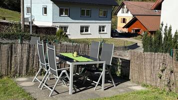 Eine Terrasse mit Tisch und Stühlen, ein Holzzaun und Häuser im Hintergrund.
