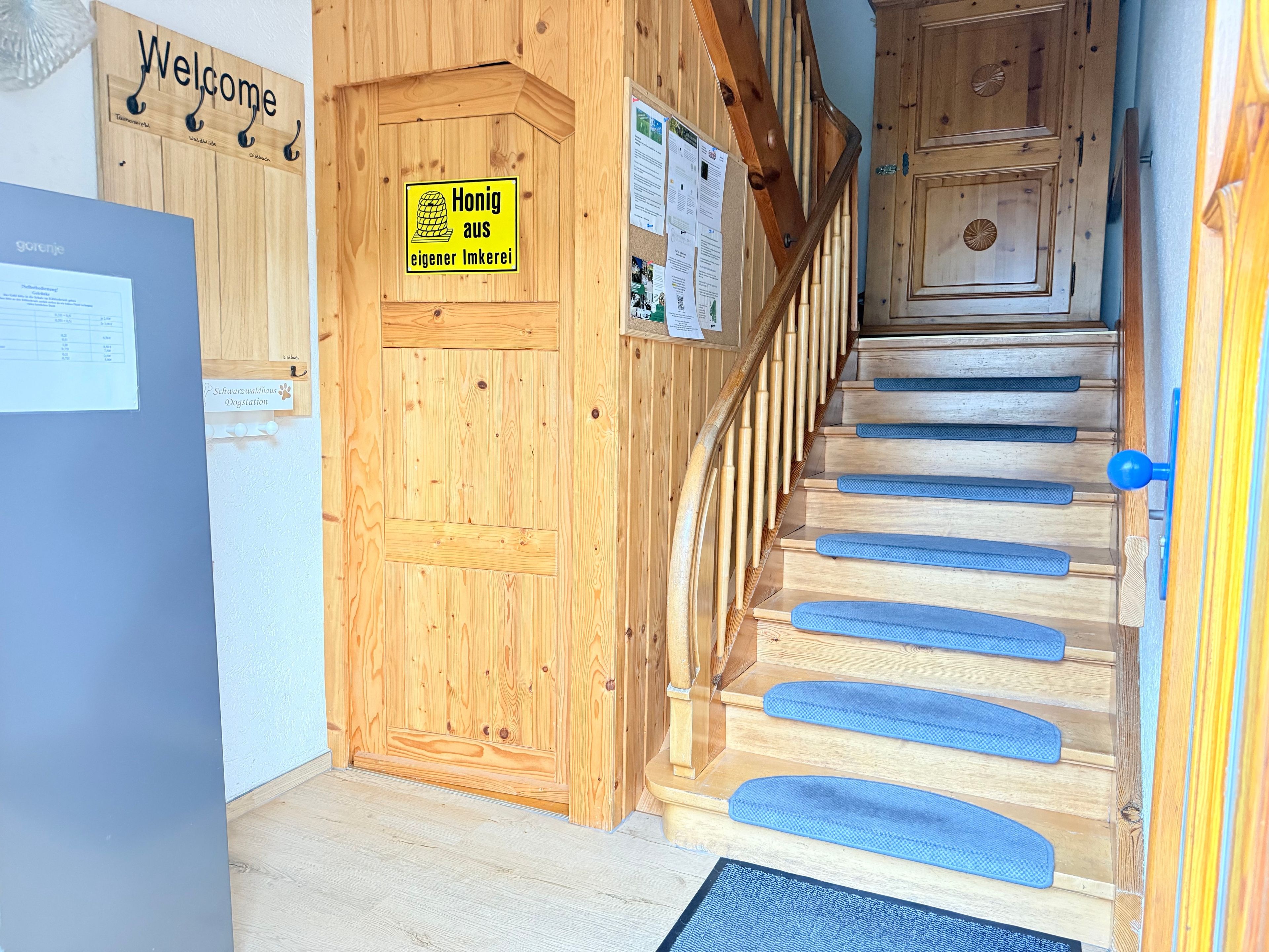Eine Holztreppe mit blauen Stufen und einer Holztür, an der ein Schild angebracht ist.