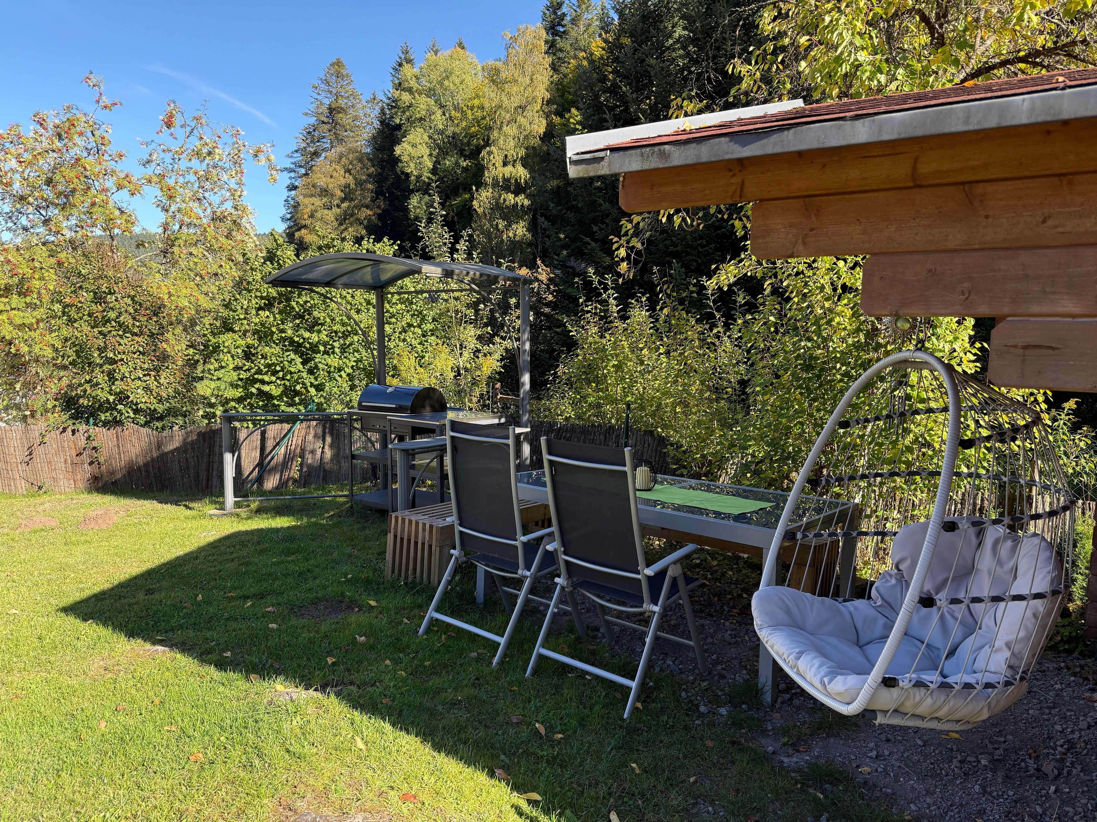 Eine Außenpatio mit Grill, Stühlen und einer Hängematte.