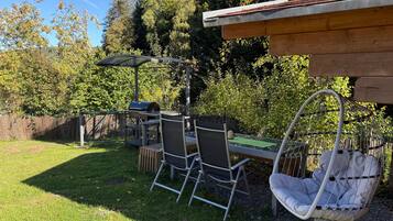 Eine Außenpatio mit Grill, Stühlen und einer Hängematte.