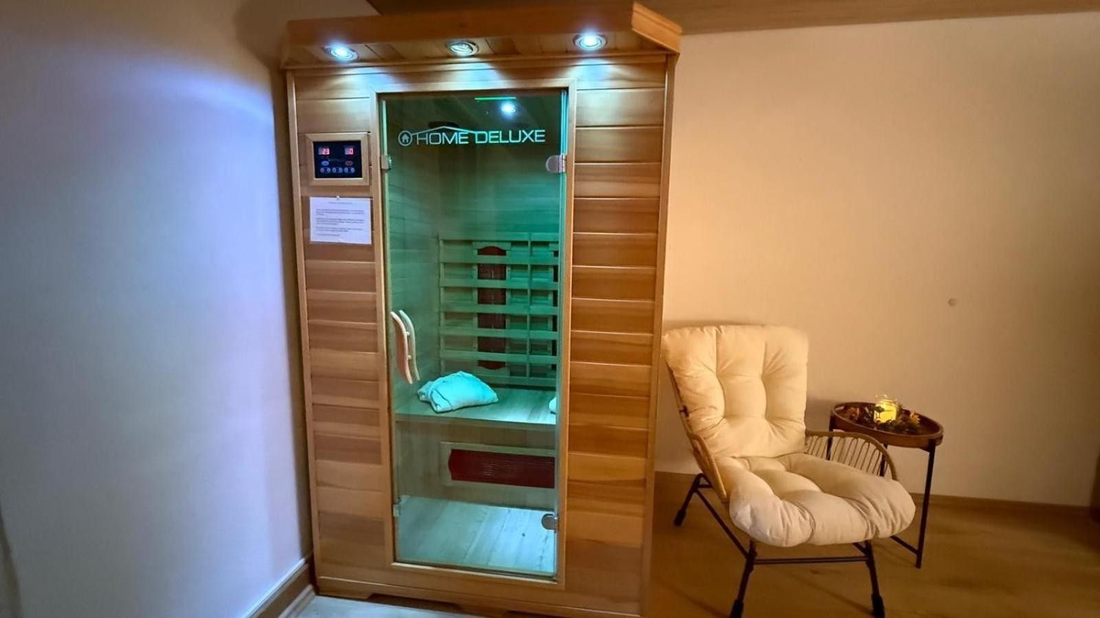 A room with a massage chair and a wooden cabinet with a glass door labeled 'HOME DELUXE'.