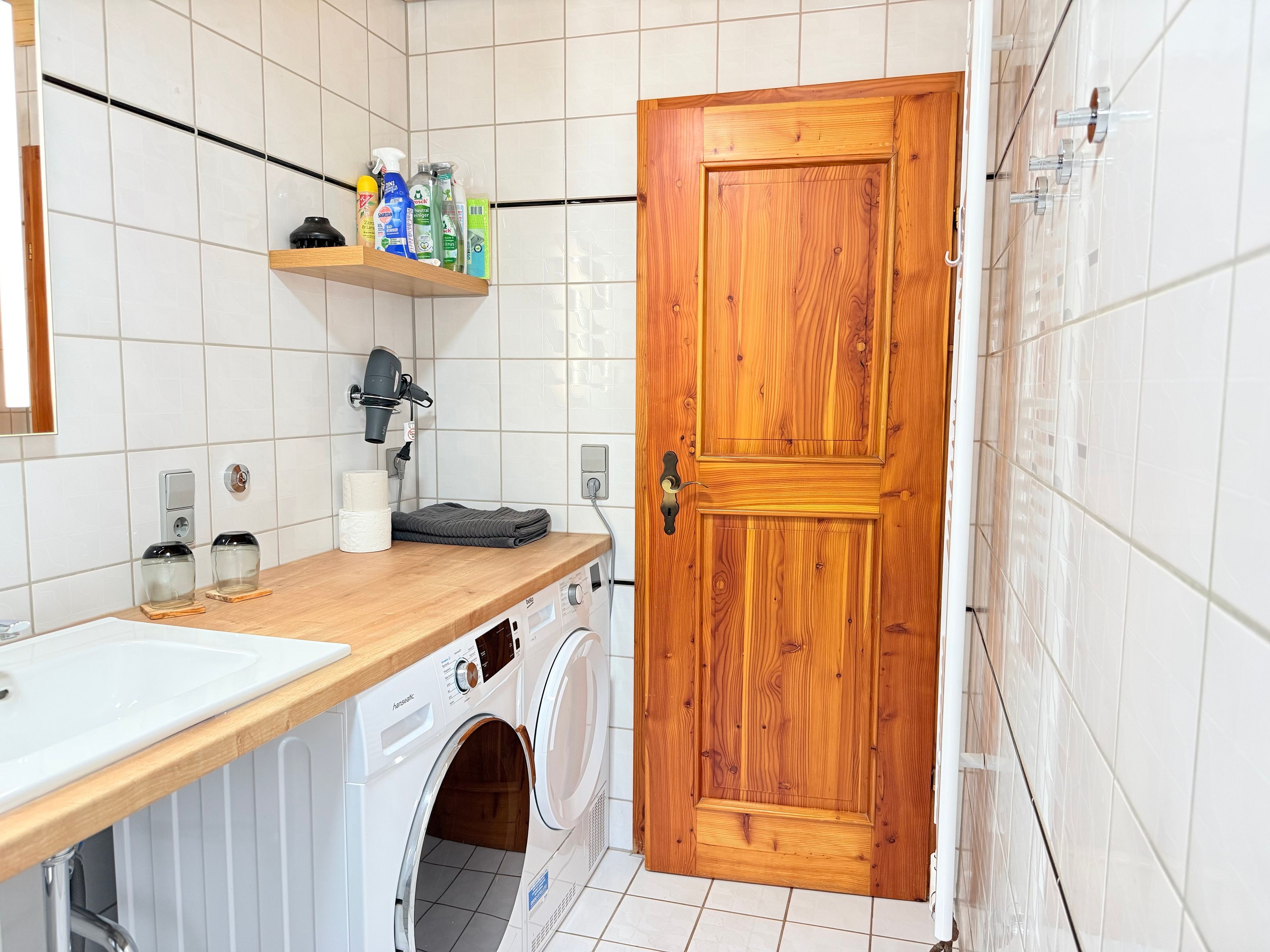 Een wasserette met een wasmachine, een droogrek en een houten deur.