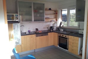 Eine kleine Küche mit Mikrowelle, Herd, Spüle und einem Fenster, das für natürliches Licht sorgt.
