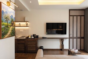 A modern living room with a flat-screen TV mounted on the wall, a sofa, and a small table with a book. - LARACINE PHU QUOC HOTEL (Phu Quoc)