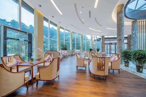 Un espacio interior amplio con suelo de madera, varios arreglos de asientos y grandes ventanales que ofrecen vistas al exterior.