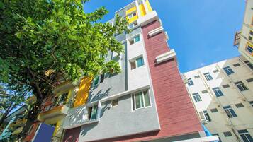 Un edificio de varios pisos con un diseño arquitectónico moderno, que presenta una combinación de colores en la fachada.