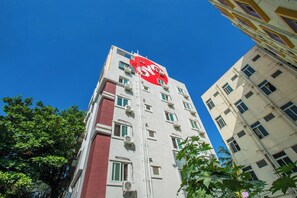 A multi-story building with a prominent red sign on the top. - Hotel O Varcity Emerald Near Ragigudda (Bangalore)