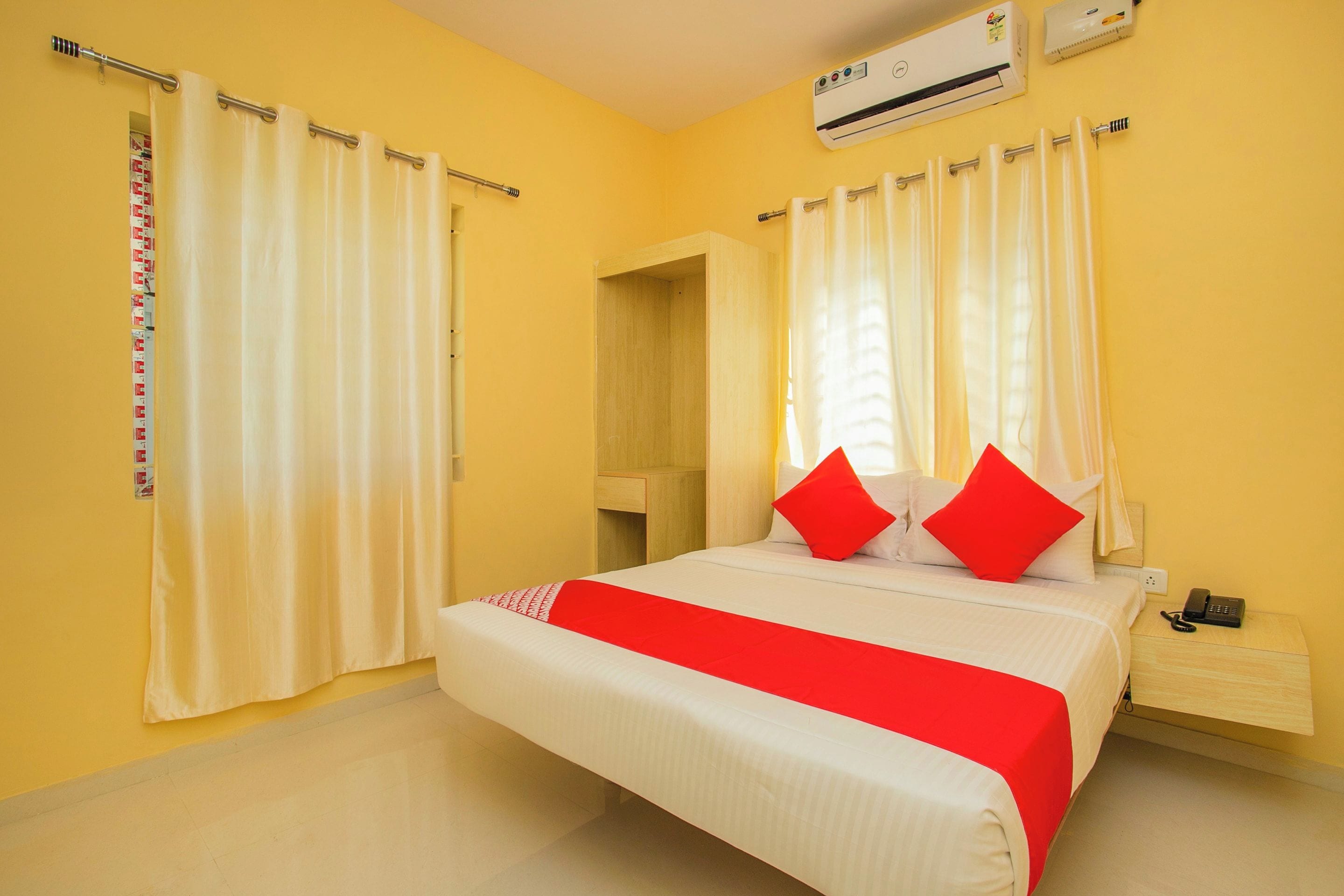 Quarto de hotel com cama, mesa de cabeceira, ar condicionado e cortinas.