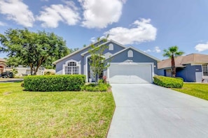A residential house with a garage, a driveway, and a well-maintained lawn. - Private Pool In Golf Resort! 4 Bedroom Home (Haines City)