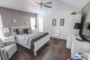 A bedroom with a bed, a chair, a TV, a ceiling fan, and a wardrobe. - Private Pool In Golf Resort! 4 Bedroom Home (Haines City)