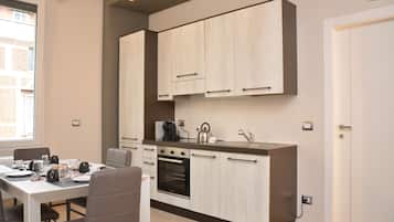 Una cucina compatta con elettrodomestici moderni, una zona pranzo con tavolo e sedie, e vista all'esterno da una finestra.