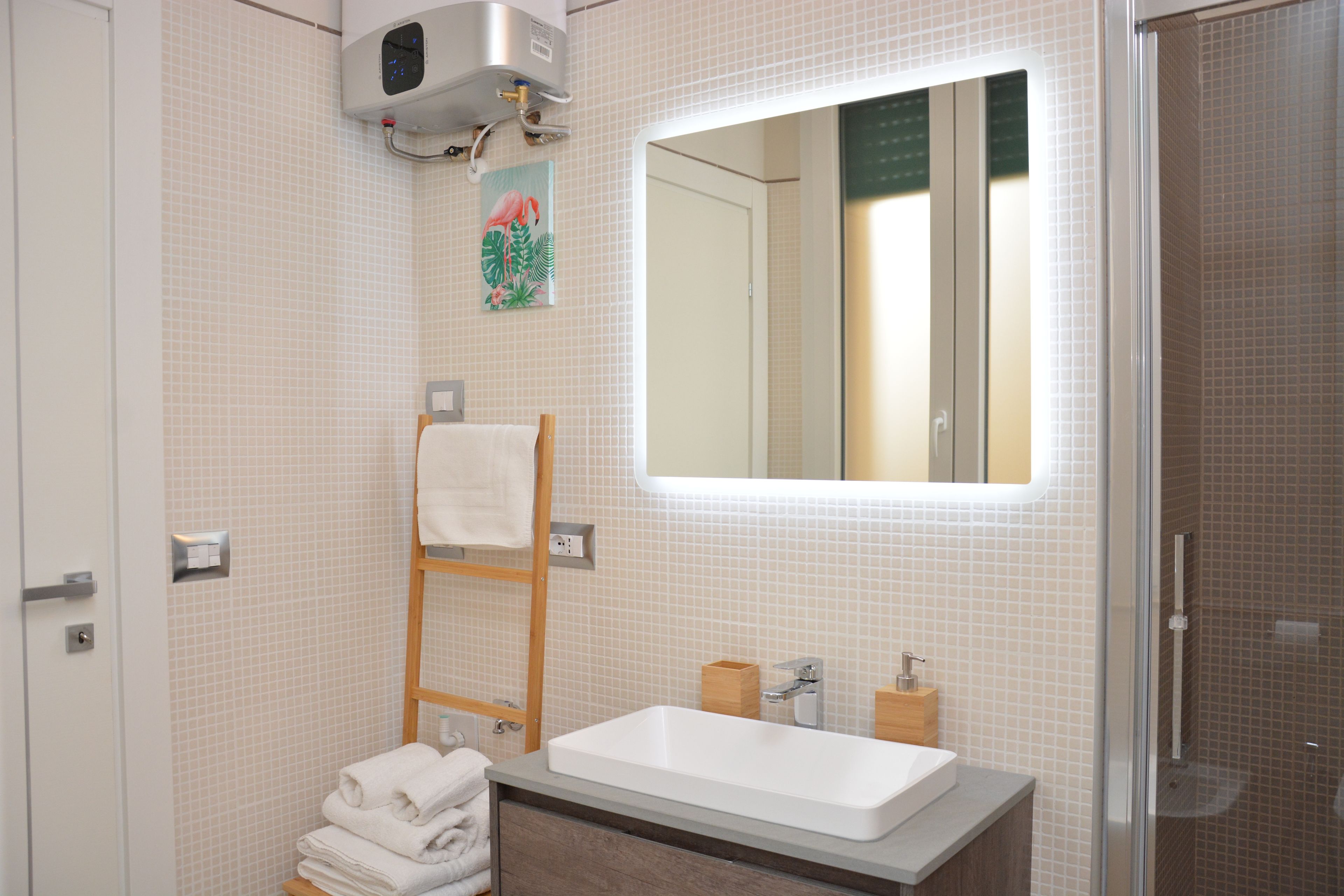 A bathroom with a white sink, a mirror, a towel rack, and a shower.