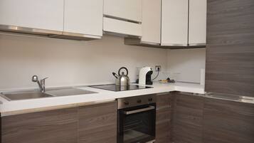 A modern kitchen with a stainless steel sink, a kettle, a coffee maker, and a built-in oven.