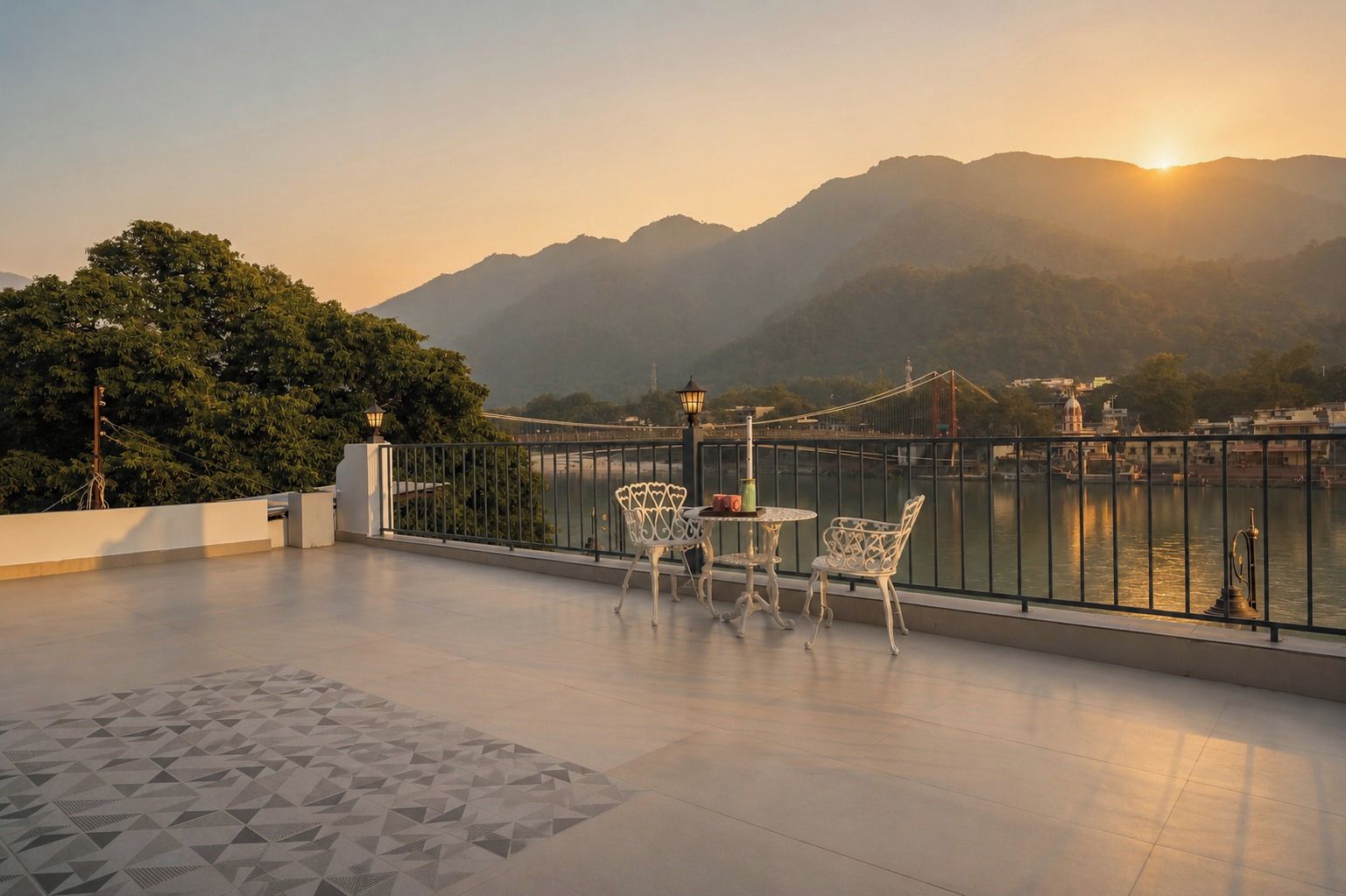 A terrace with a view of a river and mountains, featuring a table and chairs.
