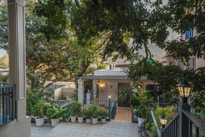 A courtyard with a staircase leading to a building, surrounded by potted plants and trees. - Amoha glasshouse 5-bedroom bungalow in tranquil Rishikesh with AC (Rishikesh)