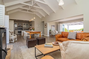 A spacious living area with a high ceiling, a dining table, a leather sofa, and a kitchen in the background. - Cloud 7 | Peaceful | Mountain & sea views | Onrus (Onrusrivier)