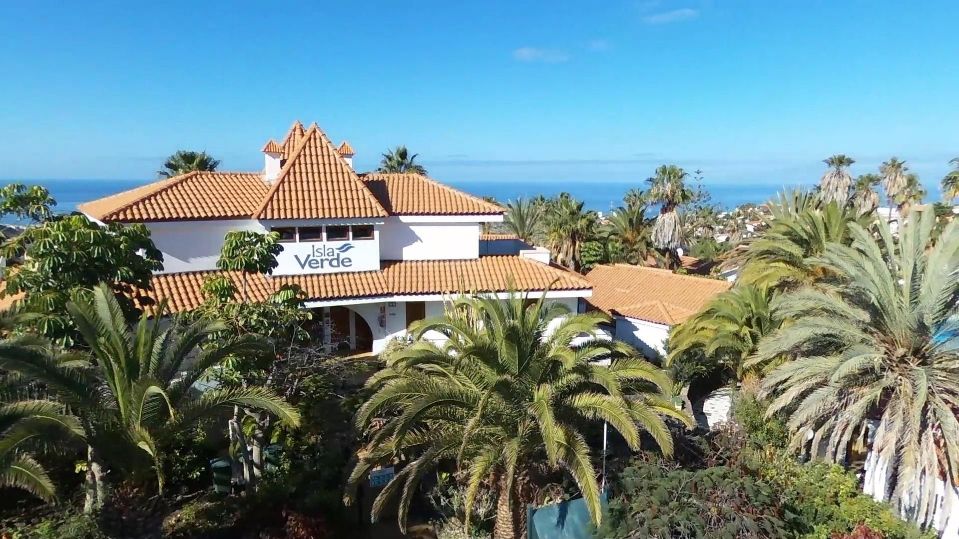 Un edificio de dos pisos con un letrero que dice 'Isla Verde' y vista al océano.