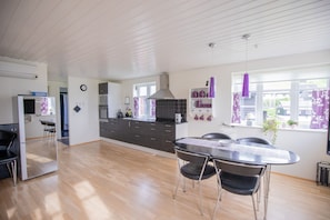 Une cuisine moderne avec un coin repas, un plancher en bois et une vue sur l’extérieur.