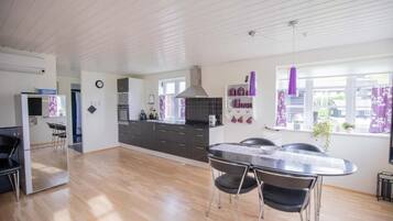 Une cuisine moderne avec un coin repas, un plancher en bois et une vue sur l’extérieur.
