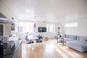A spacious living area with a dining table, sofa, and kitchen appliances. - Eystan Gard 5H (Gjógv)