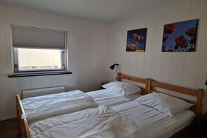 A room with two single beds, a window with blinds, and two wall-mounted paintings. - Bungalow with 2 bedrooms (Callantsoog)