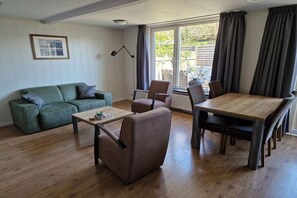 A furnished living room with a sofa, armchair, coffee table, and dining table. - Bungalow with 2 bedrooms (Callantsoog)