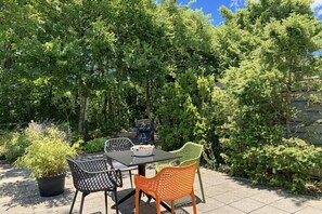 An outdoor patio with a table and chairs, surrounded by dense foliage. - Holiday home with 2 bedrooms (Julianadorp)
