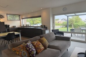 A modern living space with a sofa, dining table, and kitchen area. - Holiday home with 2 bedrooms (Julianadorp)