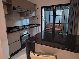 Una cocina con encimera negra, electrodomésticos de acero inoxidable y ventana con vistas al exterior.