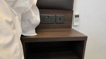 Une table de chevet en bois équipée d’une prise électrique et d’un panneau de commande, probablement pour une lampe de chevet ou de bureau.