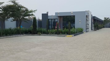 A modern building with a paved entrance area, a ladder, and a well-maintained garden.